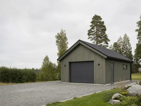 Attefallsgarage i trä vid villa på svensk tomtyta